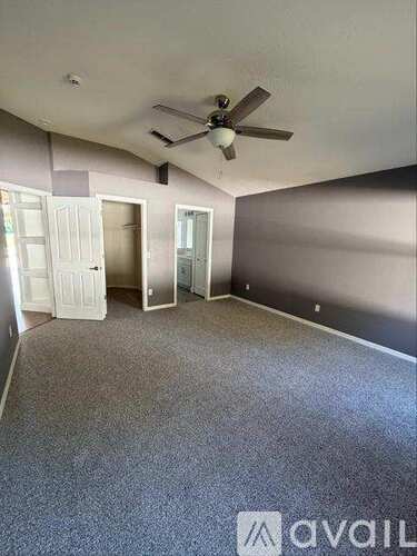 A room with a ceiling fan and carpeted floor.