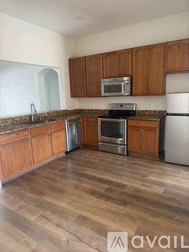 A kitchen with wooden cabinets and a stainless steel refrigerator.