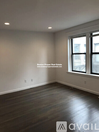 A room with wooden flooring and a window showing a city view.
