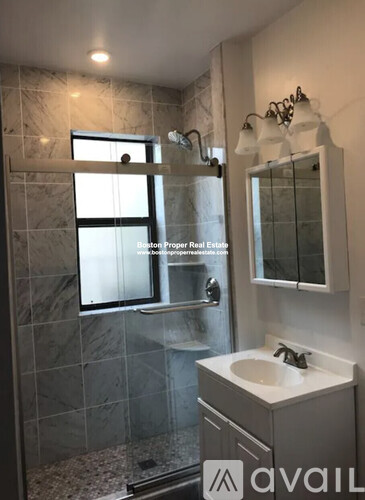 A bathroom with a marble tile shower and a white sink vanity.
