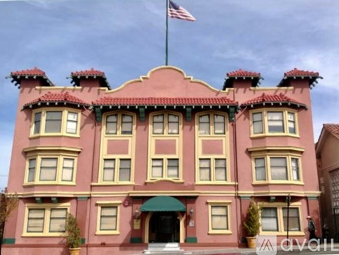 A pink building with a green awning and an American flag on top.