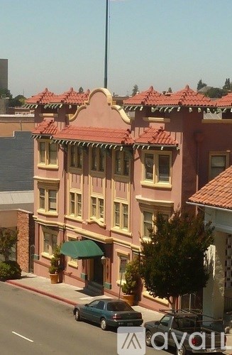 A car is parked on the street in front of a building with a red roof.