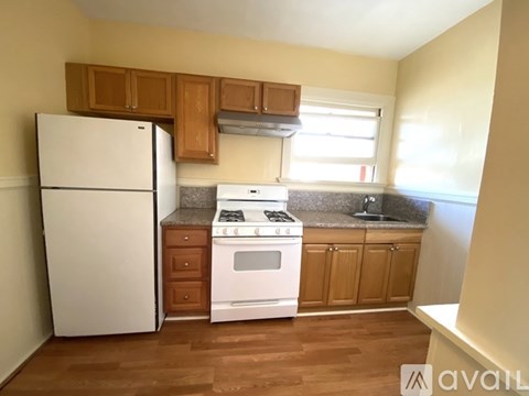 A kitchen with a white fridge, stove and wooden cabinets.