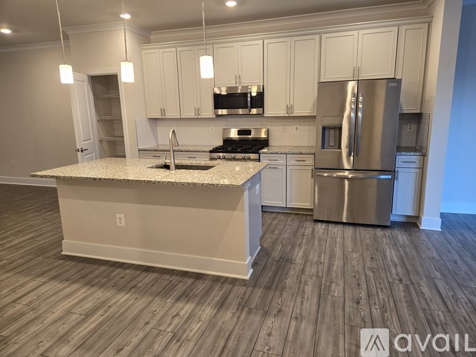 A kitchen with white cabinets and a wooden floor.