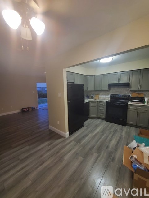 A kitchen with a black fridge and a wooden floor.