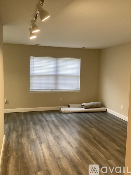 A room with wooden flooring and a window with blinds.