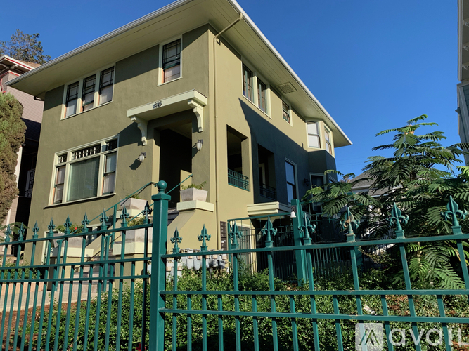 A two-story house with a green fence in front.