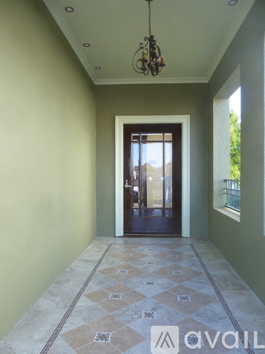 A hallway with a tiled floor and a chandelier hanging from the ceiling.