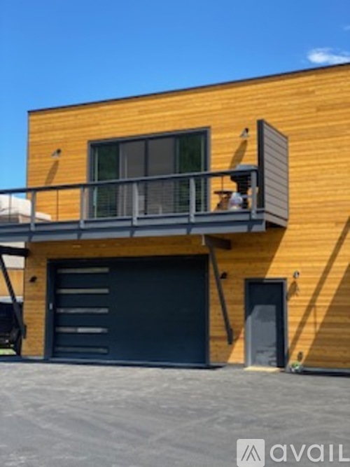A wooden building with a balcony and a black garage door.