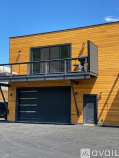 A wooden building with a balcony and a black garage door.