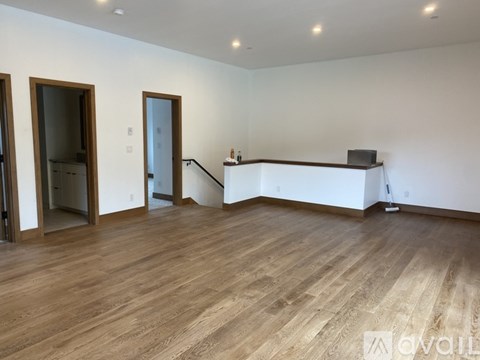 A spacious room with wooden flooring and white walls.