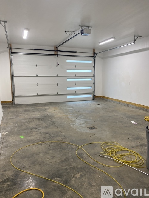 A large empty room with a concrete floor and a white wall.