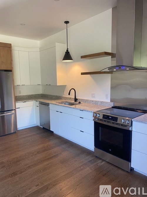 A modern kitchen with white cabinets and stainless steel appliances.