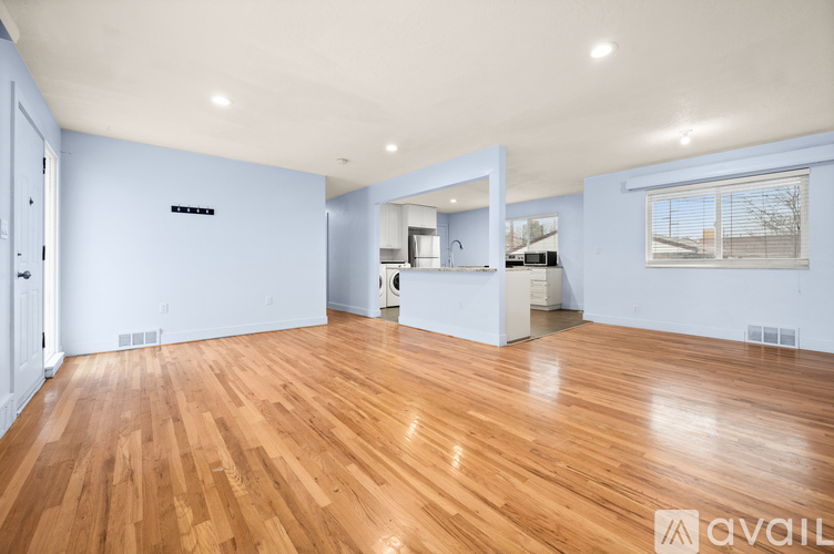 A spacious room with wooden flooring and a large mirror on the wall.