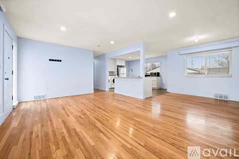 A spacious room with wooden flooring and a large mirror on the wall.