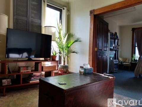 A living room with a television, a plant, and a wooden cabinet.