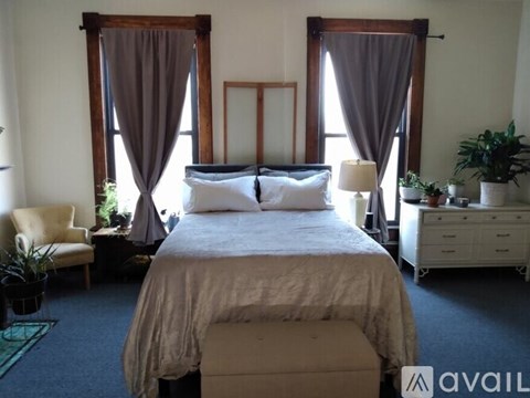 A bedroom with a large bed and a chair.