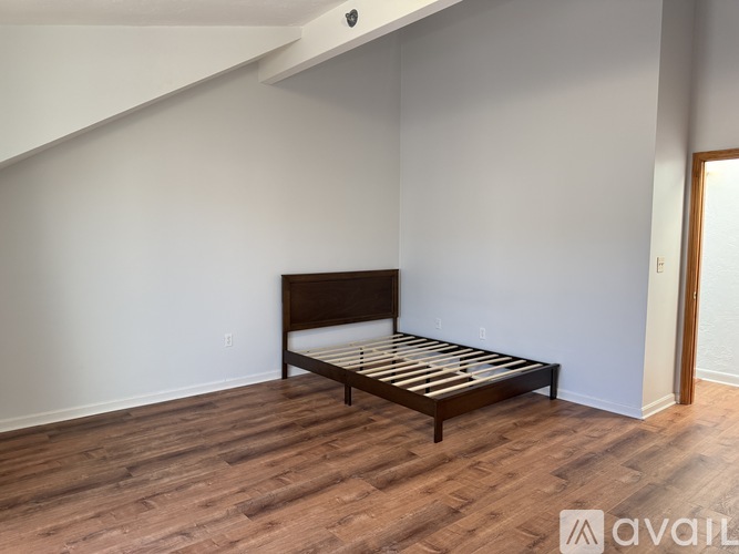 A bed with wooden slats is in a room with wooden flooring.