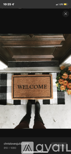 A person standing in front of a welcome mat.
