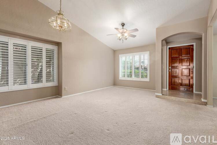 A spacious room with a ceiling fan, carpeted floor, and a door on the right.