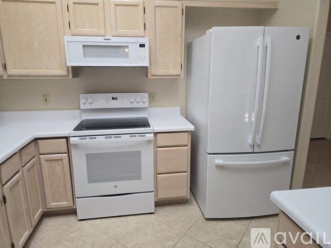 A white refrigerator stands next to a white stove in a kitchen.
