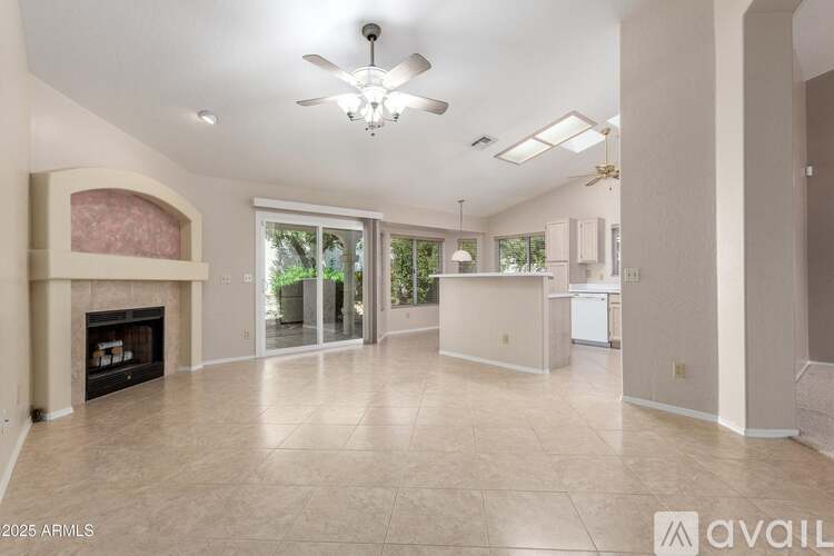 A spacious living room with a fireplace and a ceiling fan.