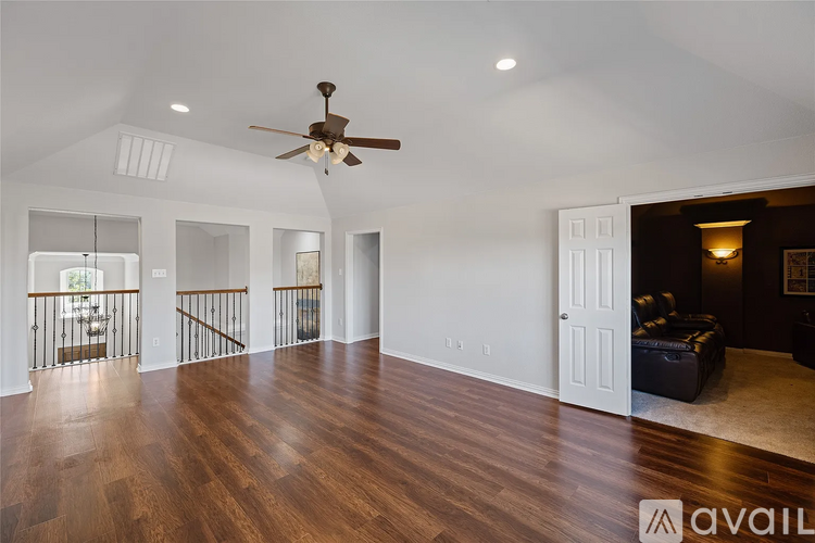 A spacious room with a ceiling fan and hardwood floors.