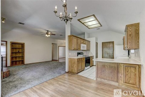 A kitchen with wooden cabinets and a chandelier.