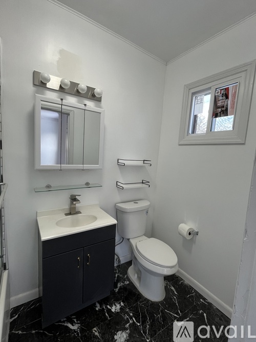 A bathroom with a toilet, sink, and mirror.