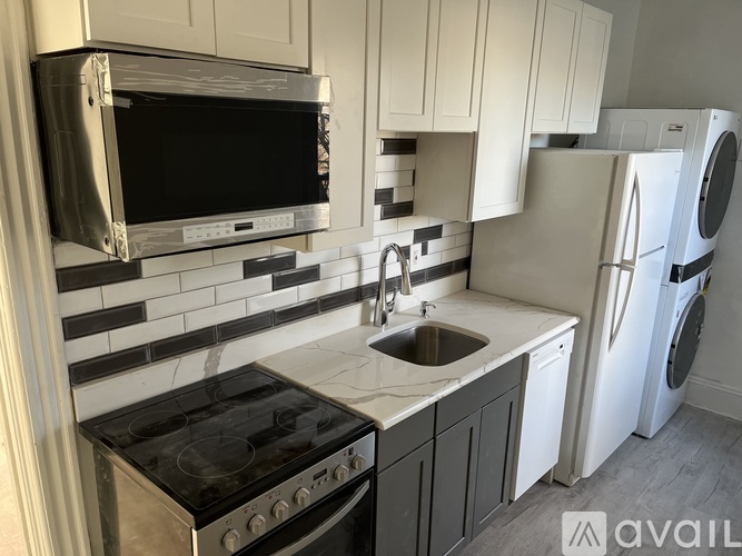 A kitchen with a black stove top oven, a white refrigerator, and a black microwave above the stove.