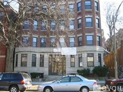 A silver car is parked in front of a brick building.