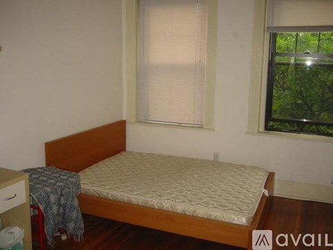 A bedroom with a bed, a nightstand, and a window with blinds.