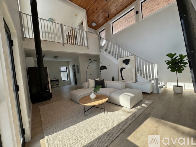 A modern living room with a black refrigerator and a wooden ceiling.