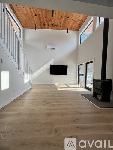 A spacious living room with wooden floors and a staircase on the left side.