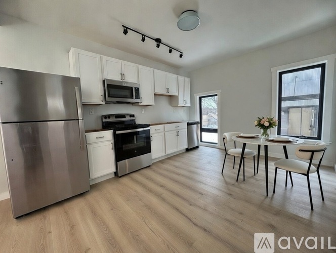 A kitchen with a refrigerator, microwave, oven, and dining table.