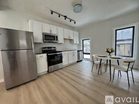 A kitchen with a refrigerator, microwave, oven, and dining table.