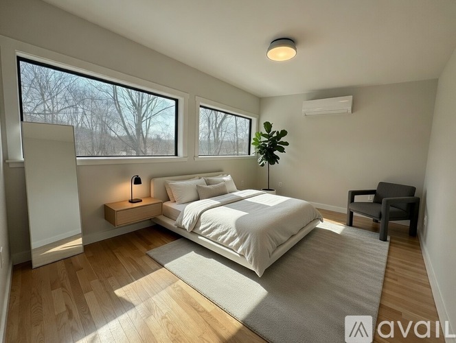 A bedroom with a large bed, a chair, and a window with a view of trees outside.