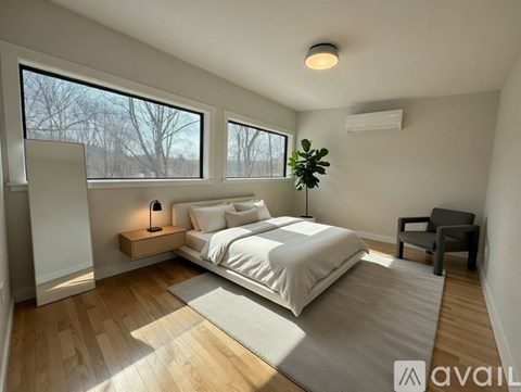 A bedroom with a large bed, a chair, and a window with a view of trees outside.