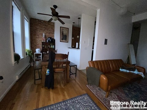 A living room with a brown couch and a ceiling fan.