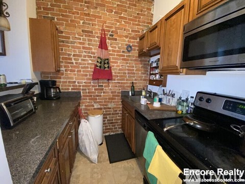 A kitchen with a black stove top oven and a red flag hanging on the wall.