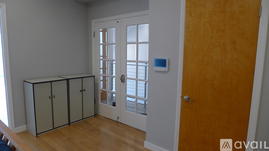 A room with a wooden floor, a white door, and a brown door.