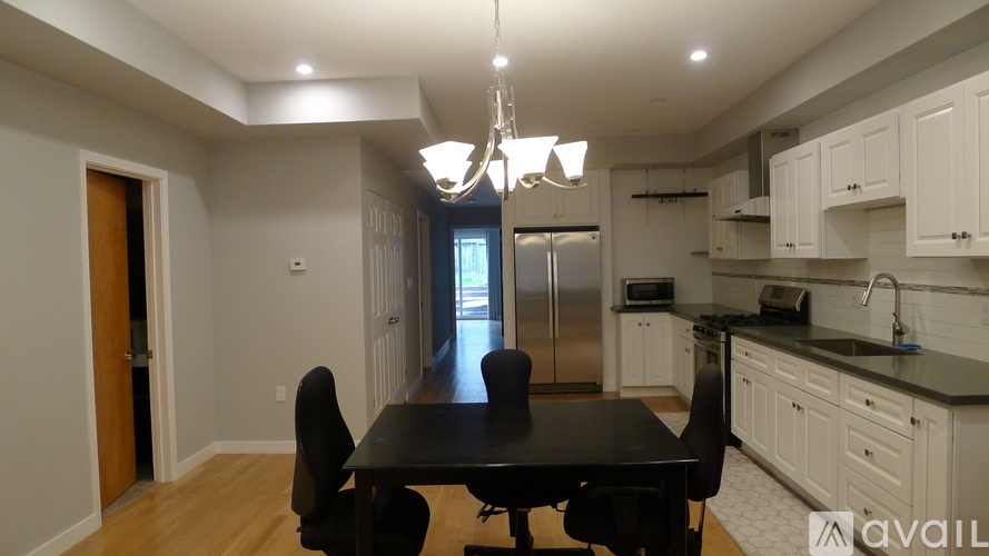 A kitchen with a table and chairs in the foreground and a refrigerator in the background.