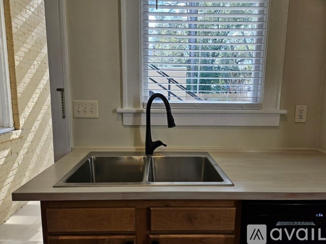 A kitchen sink with a black faucet and a window with blinds.