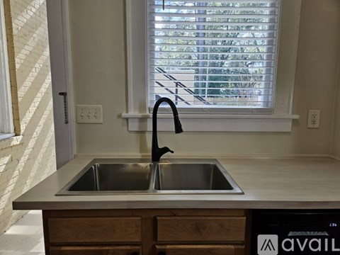 A kitchen sink with a black faucet and a window with blinds.