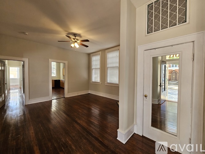 A spacious room with wood flooring and a ceiling fan.