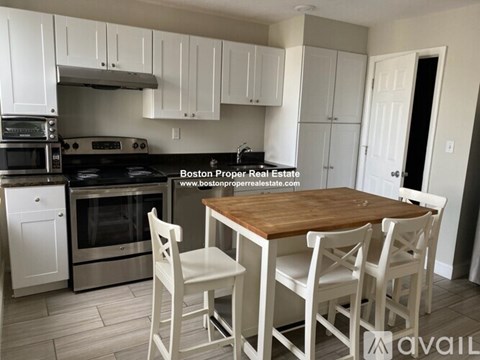 A kitchen with white cabinets and a wooden table.