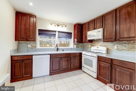 A kitchen with brown cabinets and white appliances.