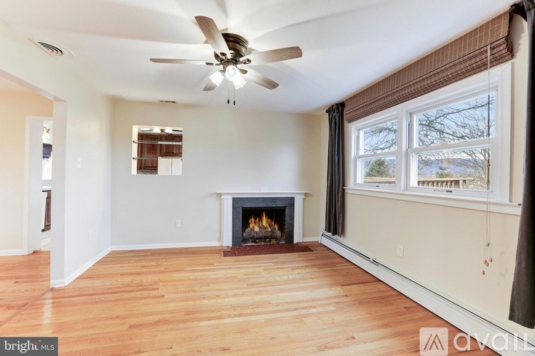 A living room with a fireplace and a ceiling fan.