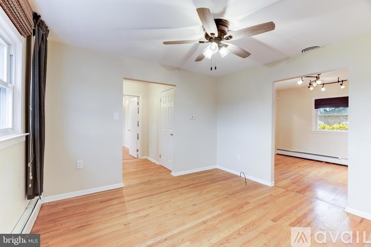 A spacious room with wooden floors and a ceiling fan.