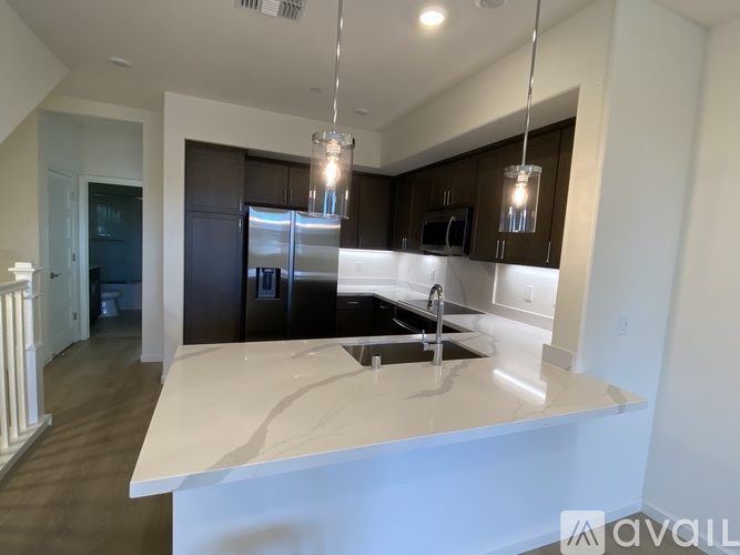 A modern kitchen with a white countertop and dark brown cabinets.